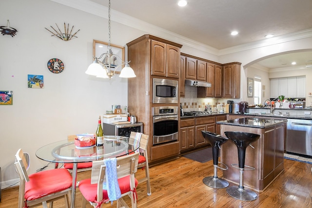 7608 Janak Dr, Houston, TX 77055 - kitchen featuring stainless steel appliances, arched walkways, dark countertops, wood finished floors, and a sink