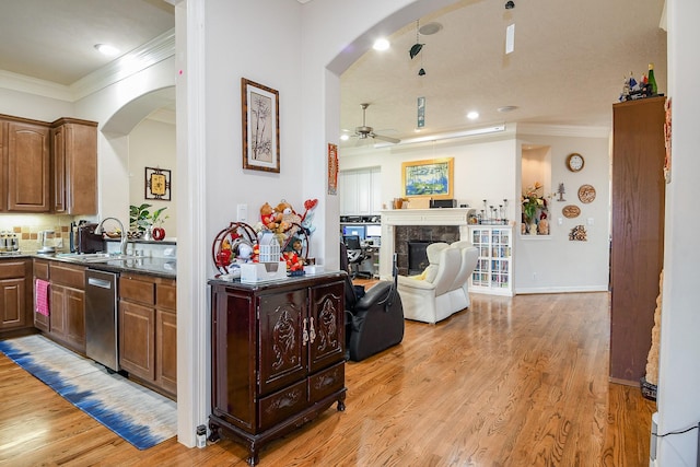 7608 Janak Dr, Houston, TX 77055 - kitchen featuring arched walkways, a sink, ceiling fan, a tile fireplace, and crown molding