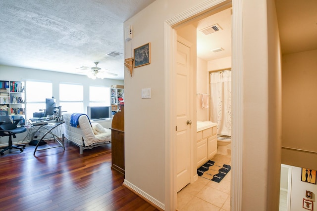 7608 Janak Dr, Houston, TX 77055 - hallway with a desk, light wood finished floors, a textured ceiling, and baseboards