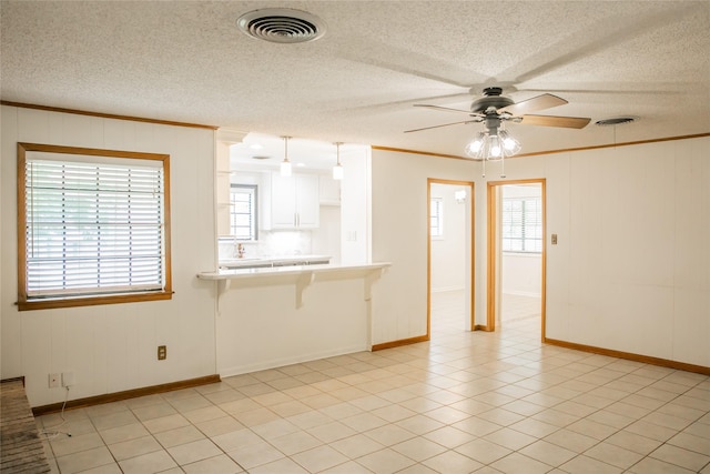 215 Edward Ln, Brenham, TX 77833 - unfurnished living room featuring ornamental molding, plenty of natural light, ceiling fan, a textured ceiling, and baseboards