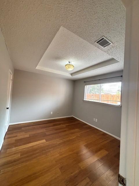 3407 S Briar Knoll Dr, Houston, TX 77082 - empty room featuring a textured ceiling, a raised ceiling, wood finished floors, and baseboards