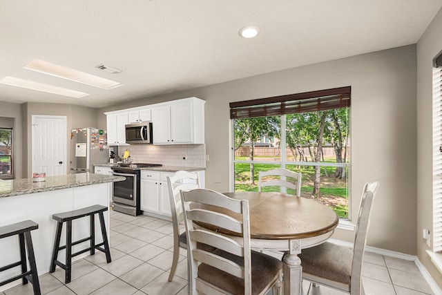 13617 Jasmine Creek Ln, Rosharon, TX 77583 - kitchen with appliances with stainless steel finishes, light tile patterned floors, backsplash, and white cabinets
