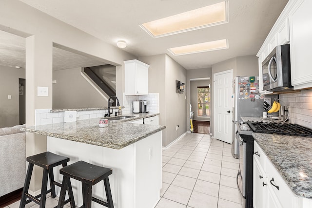 13617 Jasmine Creek Ln, Rosharon, TX 77583 - kitchen featuring stainless steel appliances, a sink, decorative backsplash, and white cabinets
