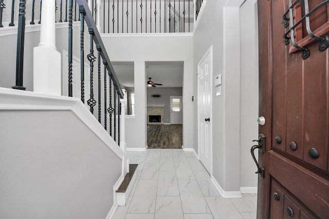 11027 Collingswood Dr, La Porte, TX 77571 - foyer entrance featuring light marble finish floors, baseboards, ceiling fan, a fireplace, and stairway