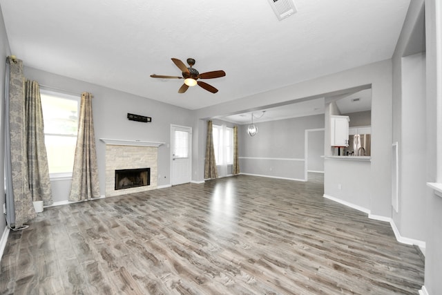11027 Collingswood Dr, La Porte, TX 77571 - unfurnished living room with baseboards, a ceiling fan, wood finished floors, a fireplace, and a chandelier