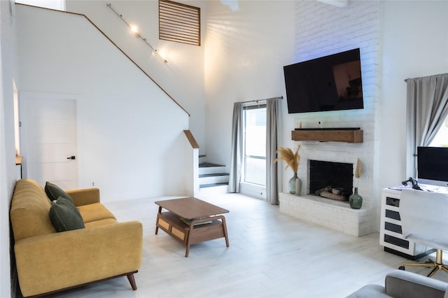 13215 Ravensway Dr, Cypress, TX 77429 - living area with a towering ceiling, a fireplace, stairs, and wood finished floors