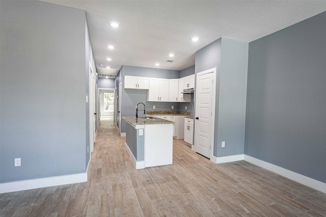5714 Pershing St A/B, Unit A/B Houston, TX 77033 - kitchen with a sink, light wood-style floors, baseboards, an island with sink, and white cabinetry