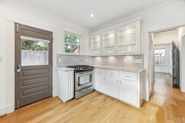 507 W 12th St, Houston, TX 77008 - kitchen featuring gas range, white cabinetry, light wood-type flooring, decorative backsplash, and light stone counters