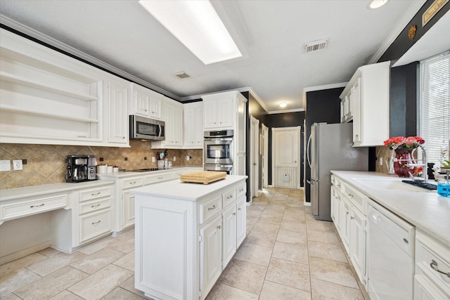 2326 Pin Hook Ct, Seabrook, TX 77586 - kitchen featuring stainless steel appliances, white cabinets, decorative backsplash, a kitchen island, and crown molding