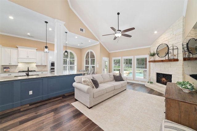 2260 Teas Crossing Dr, Conroe, TX 77304 - living area featuring dark wood-style flooring, a stone fireplace, ceiling fan, plenty of natural light, and high vaulted ceiling
