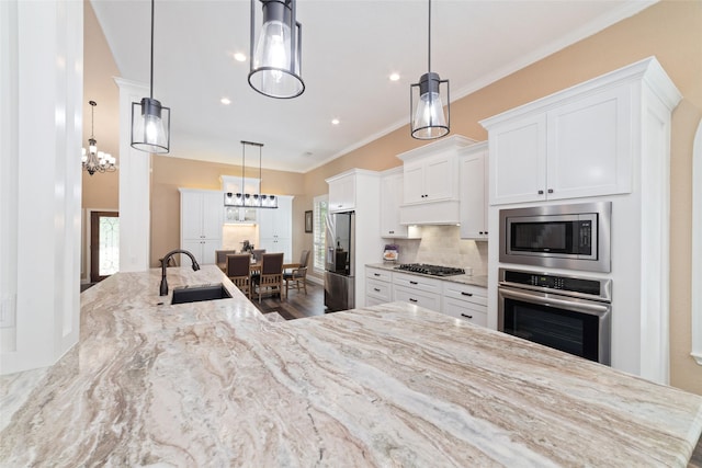 2260 Teas Crossing Dr, Conroe, TX 77304 - kitchen with a sink, stainless steel appliances, a chandelier, white cabinetry, and light stone counters
