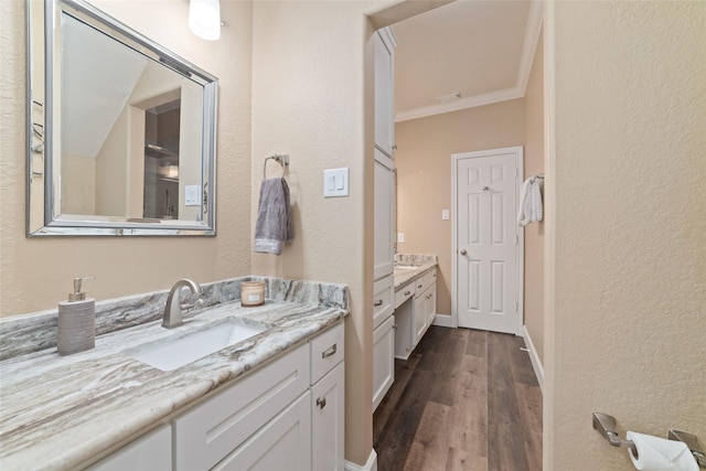 2260 Teas Crossing Dr, Conroe, TX 77304 - full bathroom with wood finished floors, two vanities, crown molding, baseboards, and a textured wall