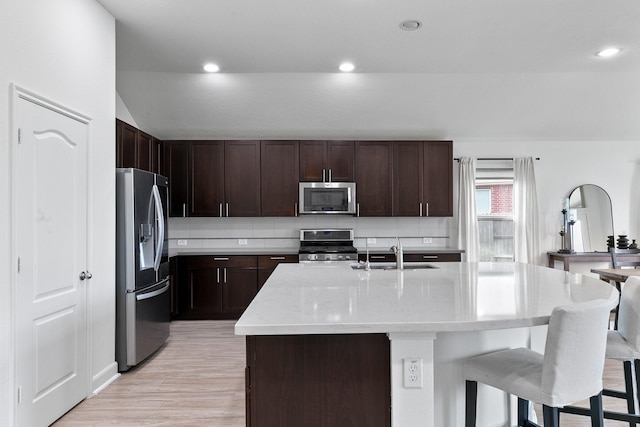 25219 Easton Ramsey Way, Richmond, TX 77406 - kitchen featuring stainless steel appliances, a sink, a kitchen breakfast bar, light wood-type flooring, and an island with sink