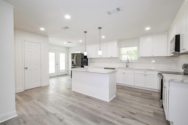 527 Fm 787th Rd E, Cleveland, TX 77327 - kitchen featuring stainless steel appliances, a sink, tasteful backsplash, a center island, and white cabinets