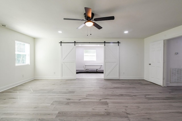 527 Fm 787th Rd E, Cleveland, TX 77327 - unfurnished room with a barn door, a ceiling fan, recessed lighting, light wood-type flooring, and baseboards