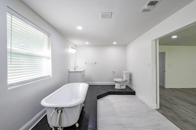 527 Fm 787th Rd E, Cleveland, TX 77327 - bathroom featuring a freestanding bath, vanity, recessed lighting, baseboards, and toilet