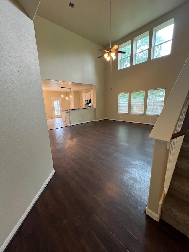 16127 Port O Call St, Crosby, TX 77532 - unfurnished living room featuring baseboards, dark wood-style flooring, stairs, a towering ceiling, and ceiling fan