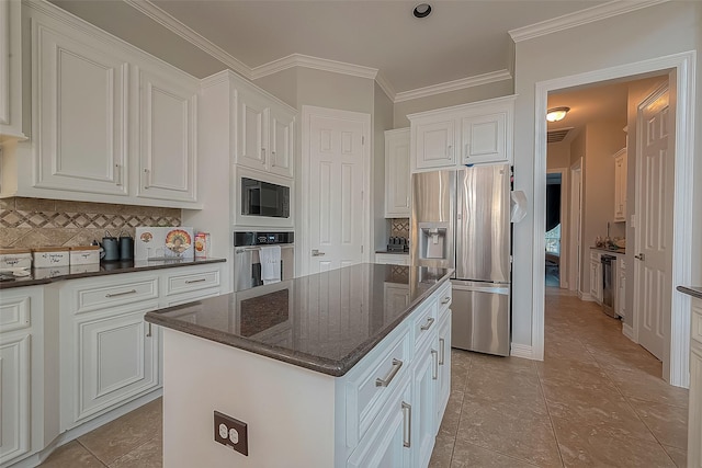 8807 Stones Throw Ln, Missouri City, TX 77459 - kitchen with stainless steel appliances, decorative backsplash, white cabinetry, a kitchen island, and crown molding