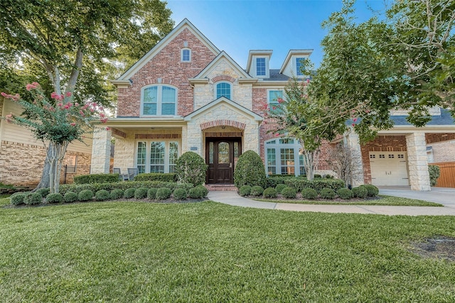 8807 Stones Throw Ln, Missouri City, TX 77459 - view of front of house featuring a front yard, a garage, driveway, brick siding, and stone siding