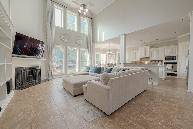 8807 Stones Throw Ln, Missouri City, TX 77459 - living area featuring ornamental molding, a fireplace, a chandelier, ceiling fan, and ornate columns