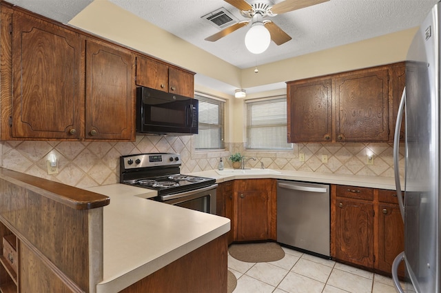 1109 Alan St, Deer Park, TX 77536 - kitchen featuring stainless steel appliances, a sink, a ceiling fan, a peninsula, and decorative backsplash