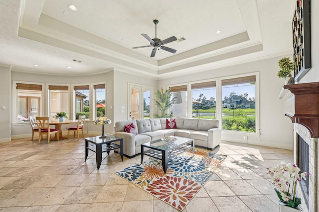 24807 Thorton Knolls Dr, Spring, TX 77389 - living area with a tray ceiling, baseboards, a ceiling fan, crown molding, and a fireplace