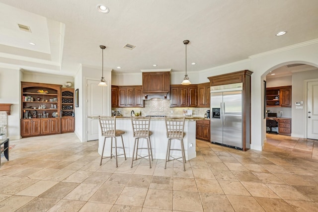 24807 Thorton Knolls Dr, Spring, TX 77389 - kitchen featuring stainless steel built in fridge, arched walkways, backsplash, an island with sink, and recessed lighting