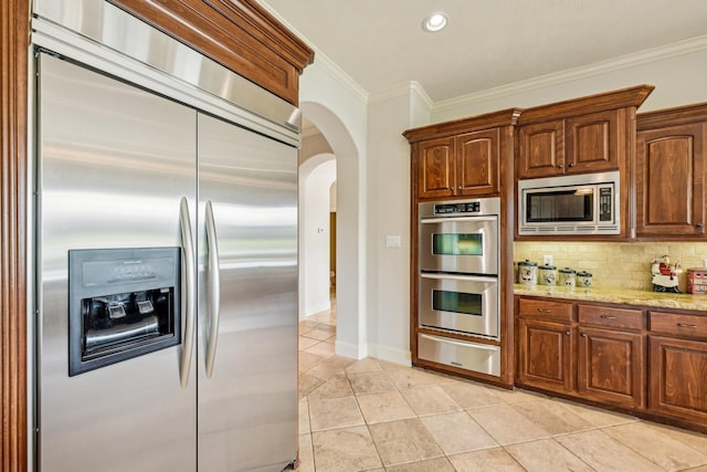 24807 Thorton Knolls Dr, Spring, TX 77389 - kitchen with built in appliances, a warming drawer, arched walkways, crown molding, and light stone countertops