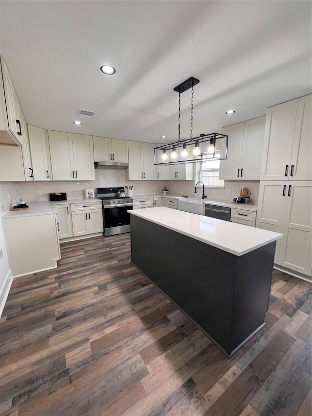1618 Del Norte St, Houston, TX 77018 - kitchen with appliances with stainless steel finishes, a sink, light countertops, dark wood finished floors, and a kitchen island