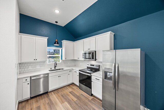 17070 Marie Village Dr, Conroe, TX 77306 - kitchen featuring stainless steel appliances, a sink, lofted ceiling, decorative backsplash, and white cabinetry