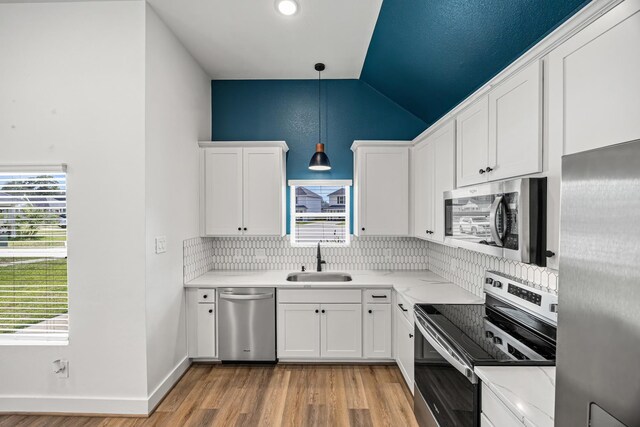 17070 Marie Village Dr, Conroe, TX 77306 - kitchen with appliances with stainless steel finishes, a sink, backsplash, lofted ceiling, and light wood-style floors
