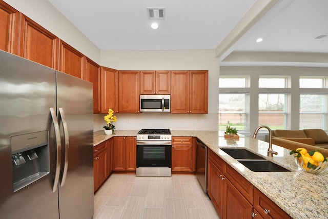 2003 Marthoman Dr, Missouri City, TX 77489 - kitchen featuring appliances with stainless steel finishes, a sink, light stone counters, recessed lighting, and brown cabinets