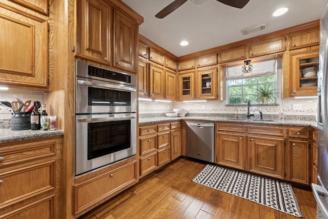 6509 Patricia St, Katy, TX 77493 - kitchen featuring appliances with stainless steel finishes, a sink, ceiling fan, backsplash, and hardwood / wood-style floors