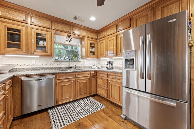 6509 Patricia St, Katy, TX 77493 - kitchen with stainless steel appliances, a sink, light stone counters, wood finished floors, and glass insert cabinets