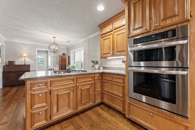 6509 Patricia St, Katy, TX 77493 - kitchen featuring stainless steel appliances, a peninsula, crown molding, dark wood finished floors, and brown cabinets