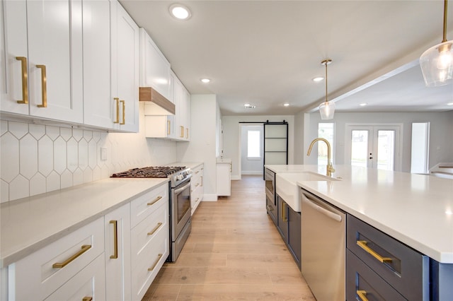 1810 Eagle Falls Ct, Houston, TX 77077 - kitchen with appliances with stainless steel finishes, a sink, a barn door, white cabinets, and decorative backsplash