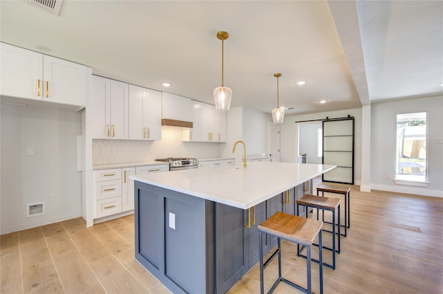 1810 Eagle Falls Ct, Houston, TX 77077 - kitchen featuring a barn door, light wood-style flooring, white cabinetry, recessed lighting, and light countertops