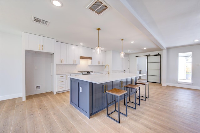 1810 Eagle Falls Ct, Houston, TX 77077 - kitchen with a barn door, range, white cabinetry, light wood-style flooring, and recessed lighting