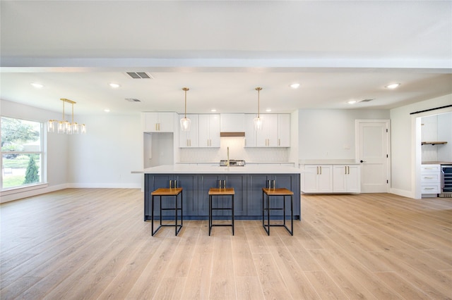 1810 Eagle Falls Ct, Houston, TX 77077 - kitchen with white cabinetry, a breakfast bar, light countertops, light wood finished floors, and decorative backsplash