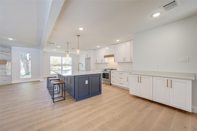 1810 Eagle Falls Ct, Houston, TX 77077 - kitchen with stainless steel gas stove, white cabinetry, a sink, light wood-type flooring, and light countertops