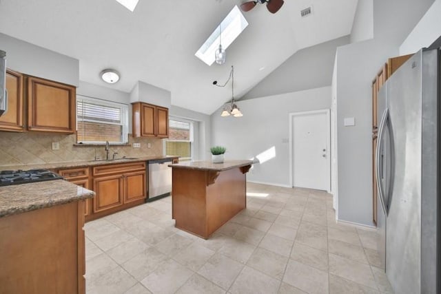 1223 Berrystone Trl, Missouri City, TX 77459 - kitchen with stainless steel appliances, a sink, a skylight, brown cabinets, and tasteful backsplash