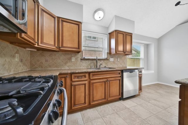 1223 Berrystone Trl, Missouri City, TX 77459 - kitchen featuring appliances with stainless steel finishes, a sink, brown cabinetry, and vaulted ceiling