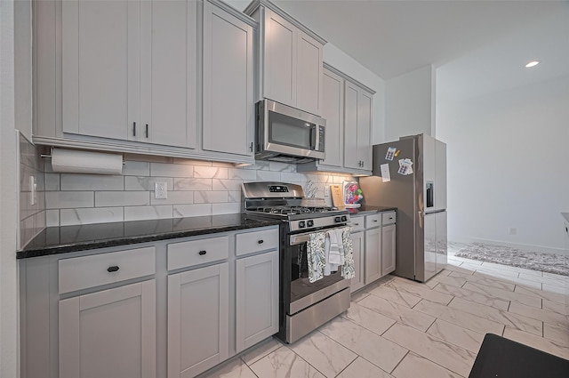 4507 Mustang Run Dr, Rosenberg, TX 77469 - kitchen featuring appliances with stainless steel finishes, light marble finish flooring, dark stone counters, decorative backsplash, and gray cabinets
