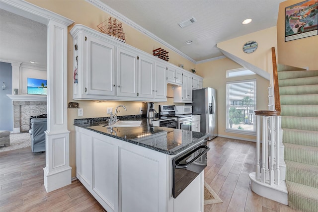 247 Isles End Rd, Tiki Island, TX 77554 - kitchen with a sink, appliances with stainless steel finishes, dark stone counters, decorative columns, and light wood-type flooring