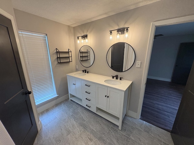 1204 Osborne Dr, Friendswood, TX 77546 - full bathroom featuring a textured ceiling, baseboards, and double vanity