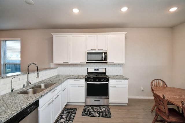 7419 French Quarter Ct, Fulshear, TX 77441 - kitchen featuring stainless steel appliances, a sink, tasteful backsplash, light stone counters, and white cabinets