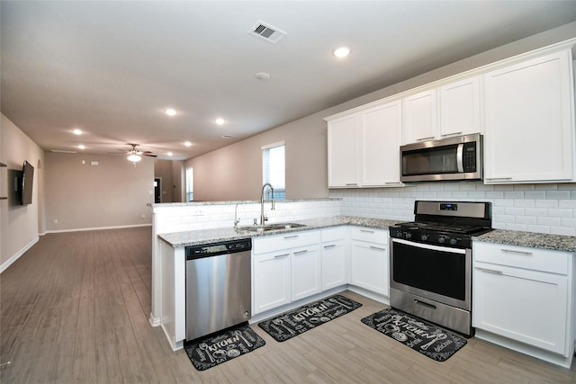 7419 French Quarter Ct, Fulshear, TX 77441 - kitchen featuring appliances with stainless steel finishes, a sink, a peninsula, backsplash, and white cabinets