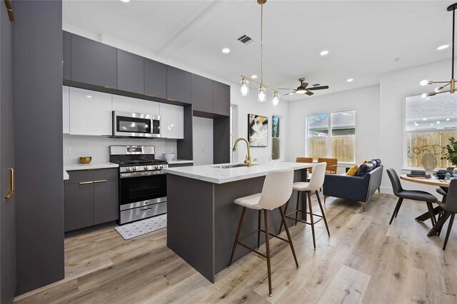 1805 Emir St Unit D, Houston, TX 77009 - kitchen with appliances with stainless steel finishes, a sink, open floor plan, a kitchen bar, and light wood-style floors