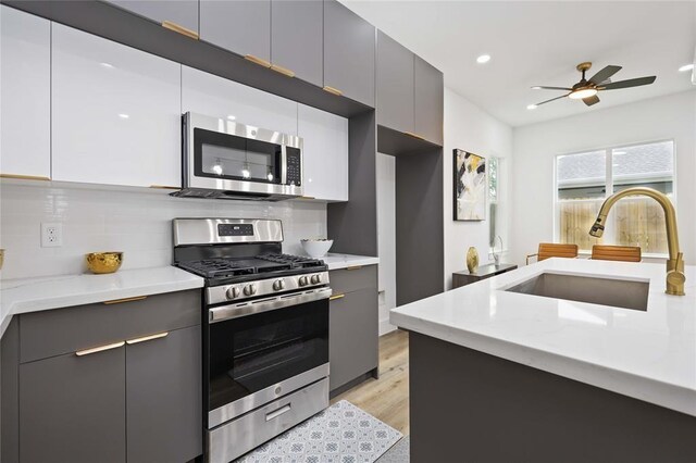 1805 Emir St Unit D, Houston, TX 77009 - kitchen featuring appliances with stainless steel finishes, a sink, modern cabinets, decorative backsplash, and light wood-type flooring