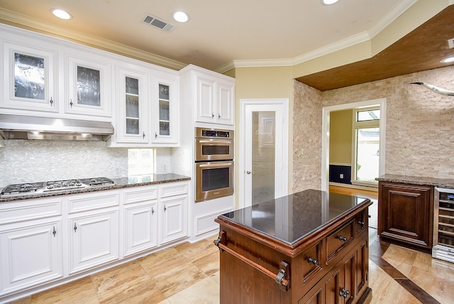 3911 Fielder Cir, Missouri City, TX 77459 - kitchen with appliances with stainless steel finishes, under cabinet range hood, dark stone counters, crown molding, and glass insert cabinets